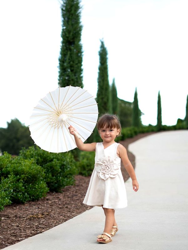 Little girl with a white parasol on a cypress-lined path