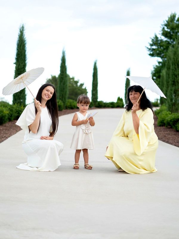 Grandmother, mother and daughter with parasols on a garden path