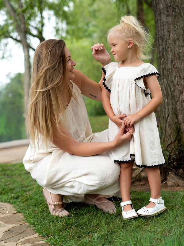 Mother kneeling beside her daughter under a willow