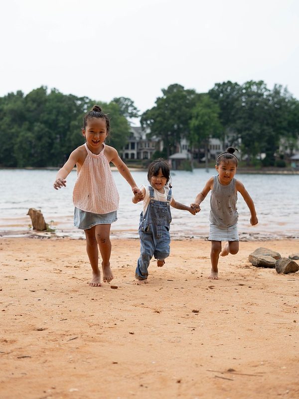 Three sisters running hand in hand along the shore