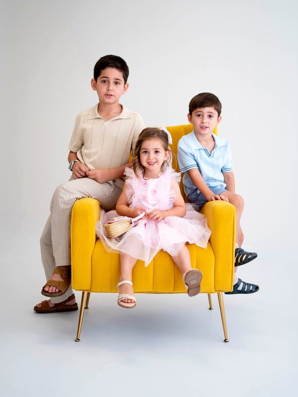 Two brothers and their sister on a yellow velvet armchair
